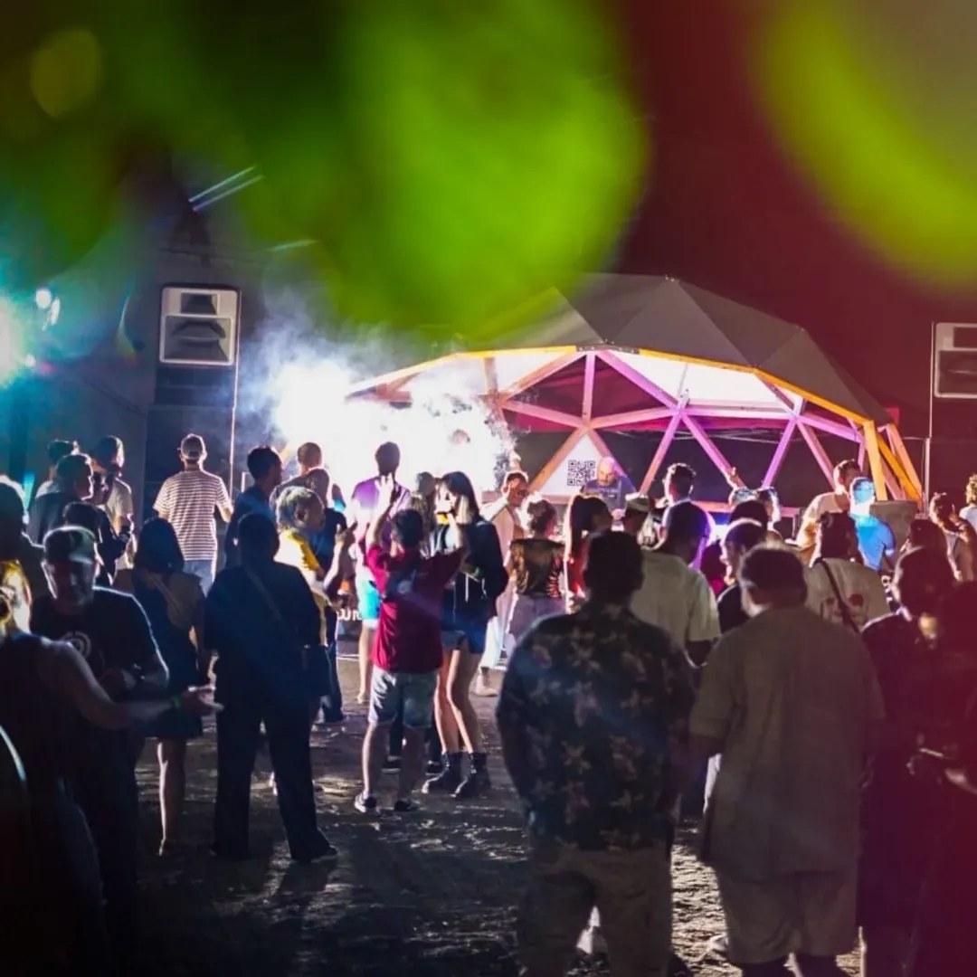 Public dansant sous un dôme géodésique éclairé, festival électro 2025